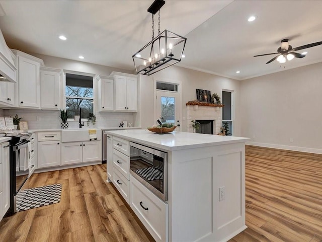 kitchen featuring white cabinetry, a kitchen island, built in microwave, and light countertops