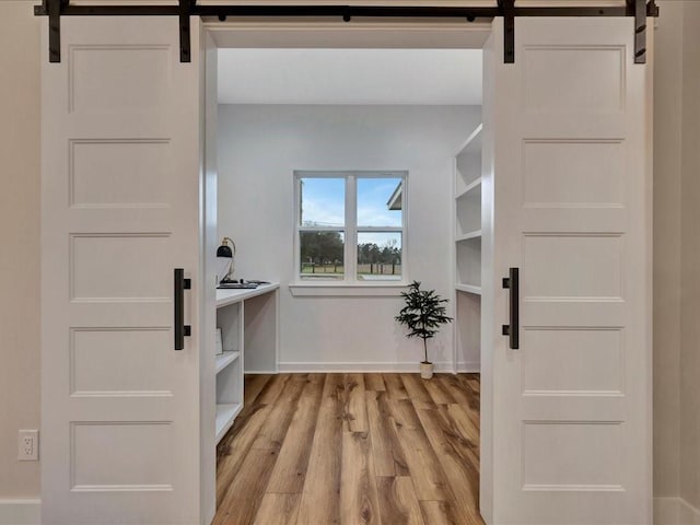 walk in closet featuring light wood-type flooring and a barn door