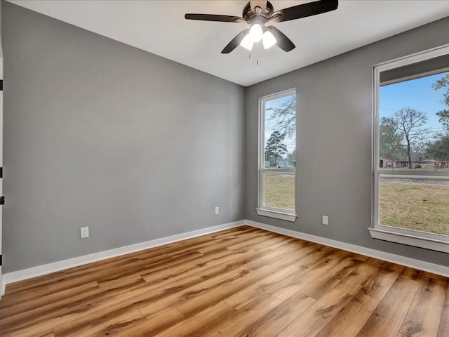 empty room with light wood finished floors, baseboards, and a ceiling fan