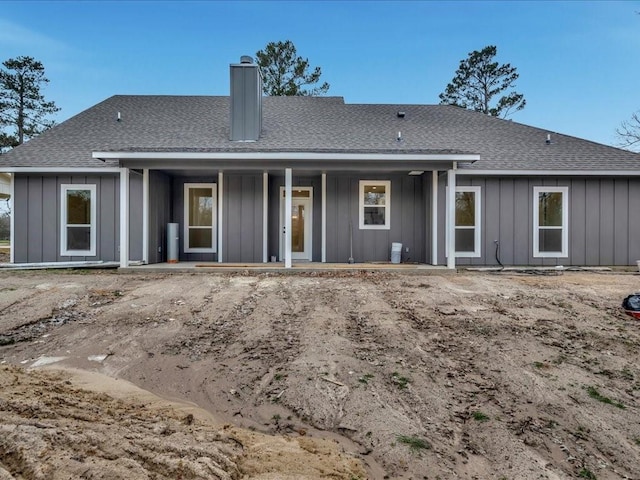 back of property with a chimney, board and batten siding, and roof with shingles