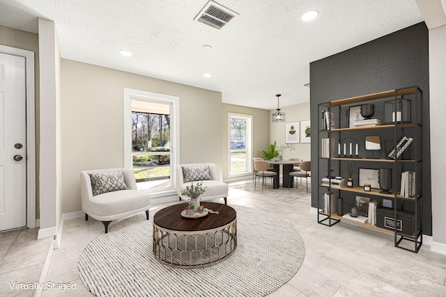 sitting room with a textured ceiling, recessed lighting, visible vents, and baseboards