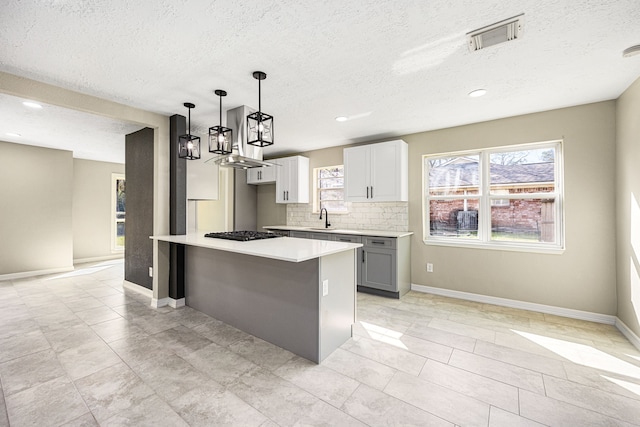 kitchen with a sink, visible vents, light countertops, tasteful backsplash, and pendant lighting