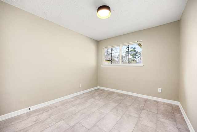 unfurnished room with a textured ceiling and baseboards