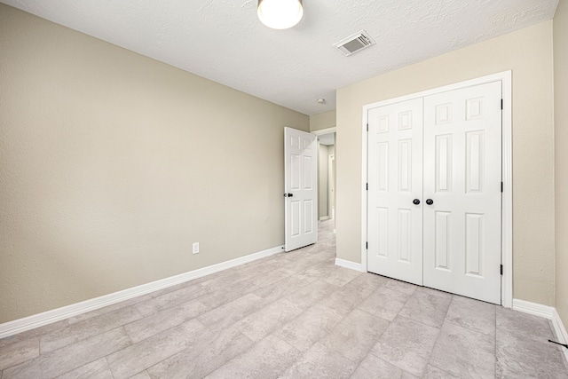 unfurnished bedroom with baseboards, a textured ceiling, visible vents, and a closet