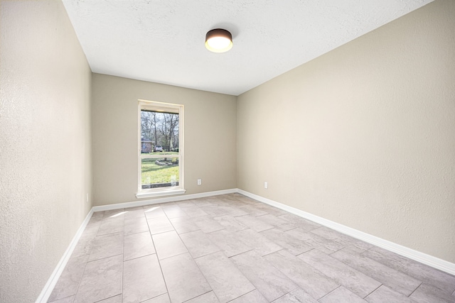 unfurnished room featuring a textured wall, a textured ceiling, and baseboards