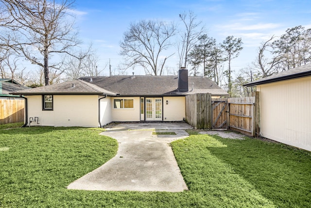 rear view of property featuring french doors, brick siding, a patio, a chimney, and a gate