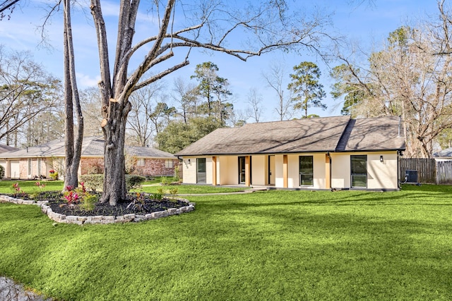 view of front of house with stucco siding, a front yard, fence, and central air condition unit