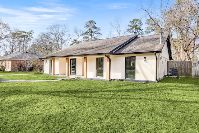 view of front facade featuring central air condition unit, fence, a front lawn, and brick siding