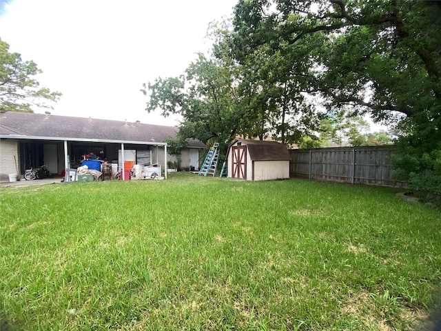 view of yard with a shed, fence, an attached carport, and an outdoor structure