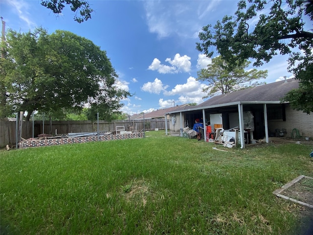 view of yard featuring a carport and a fenced backyard