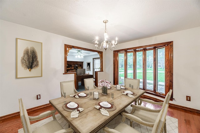 dining area featuring light wood-style floors, a textured ceiling, baseboards, and an inviting chandelier