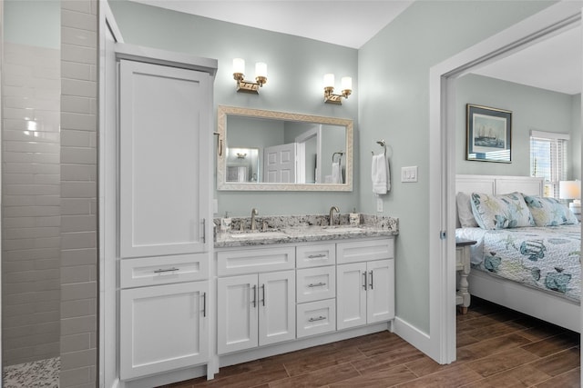 ensuite bathroom featuring a sink, double vanity, ensuite bath, and wood tiled floor