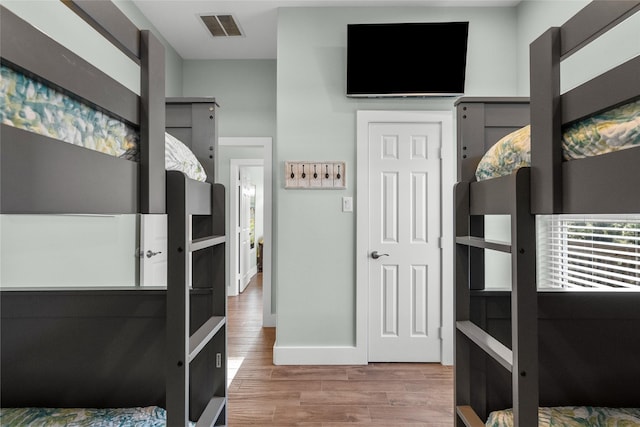 bedroom featuring visible vents, baseboards, and wood finished floors