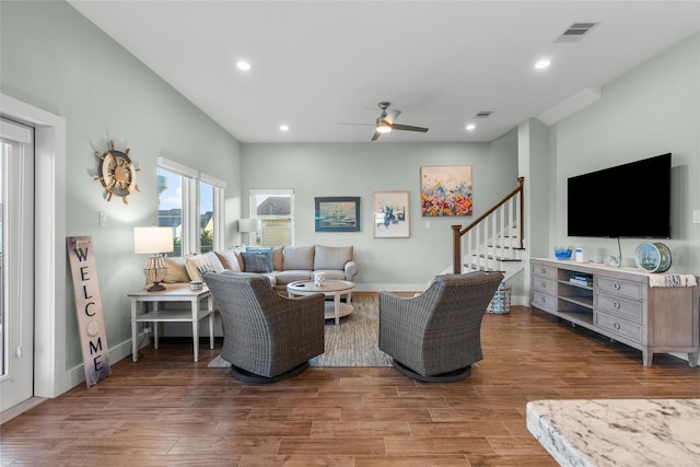 living area with recessed lighting, wood finished floors, visible vents, and stairs