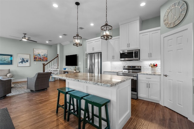 22318 Vista Del Mar, Galveston, TX 77554 - kitchen with a center island, open floor plan, appliances with stainless steel finishes, ceiling fan with notable chandelier, and backsplash
