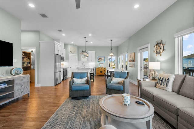 living area with a notable chandelier, dark wood finished floors, visible vents, and recessed lighting