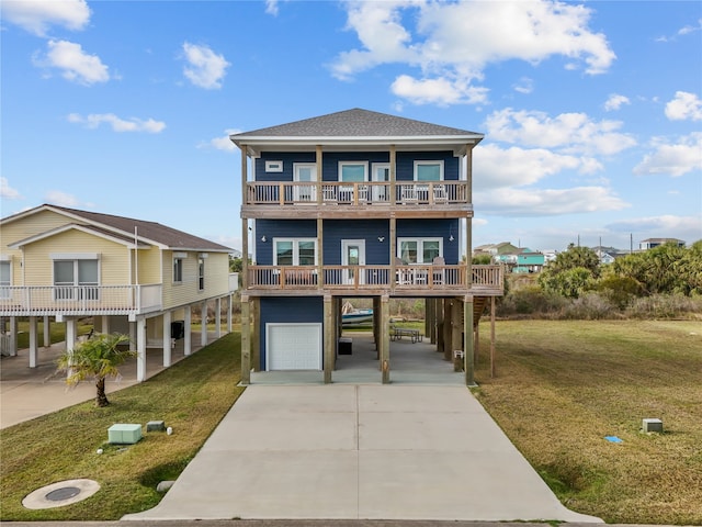 raised beach house with a garage, concrete driveway, a front lawn, and a carport