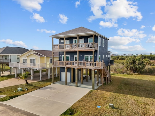 raised beach house with roof with shingles, concrete driveway, a balcony, a carport, and a front lawn