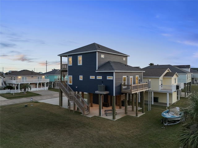 back of property with a patio, a yard, stairway, roof with shingles, and a residential view