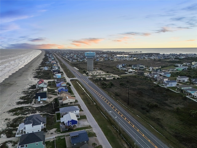 aerial view at dusk with a water view and a view of the beach