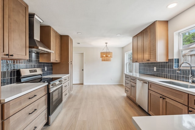 kitchen with a sink, stainless steel appliances, brown cabinetry, and light countertops