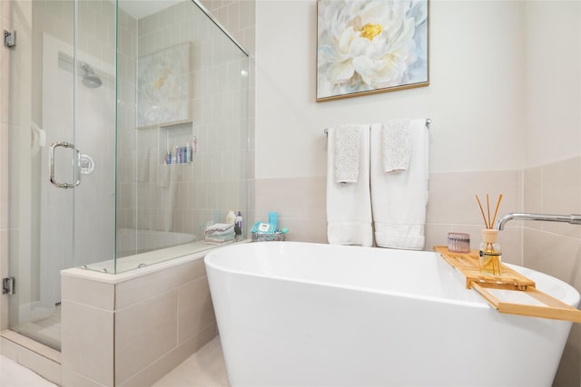 full bathroom with a shower stall, a freestanding bath, and tile walls