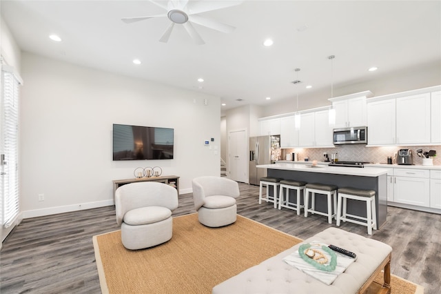 living room with dark wood-style flooring, recessed lighting, a ceiling fan, baseboards, and stairs