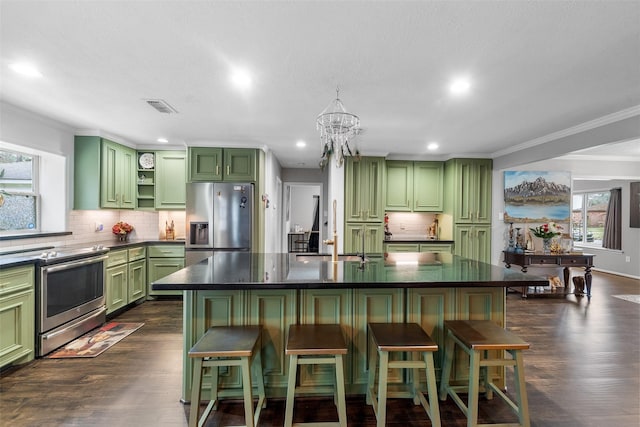 kitchen featuring a breakfast bar area, stainless steel appliances, visible vents, a center island with sink, and green cabinetry