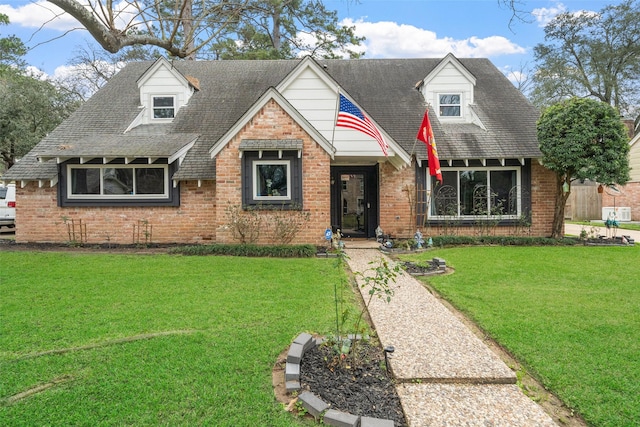 view of front of house featuring a shingled roof, brick siding, and a front lawn