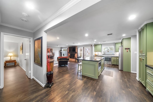 kitchen with a breakfast bar, green cabinets, appliances with stainless steel finishes, open floor plan, and a kitchen island