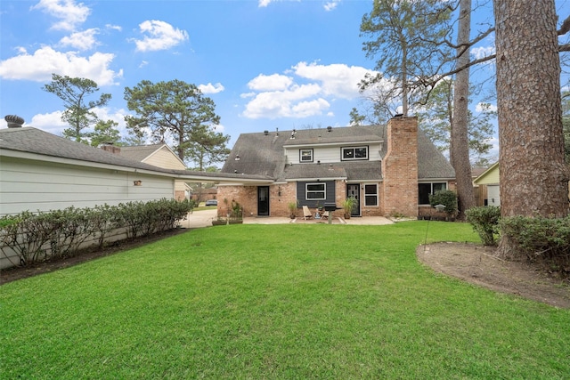 rear view of property featuring a patio, a yard, a chimney, and brick siding