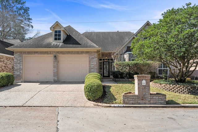 view of front facade with a garage, concrete driveway, brick siding, and roof with shingles