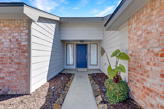 doorway to property featuring brick siding