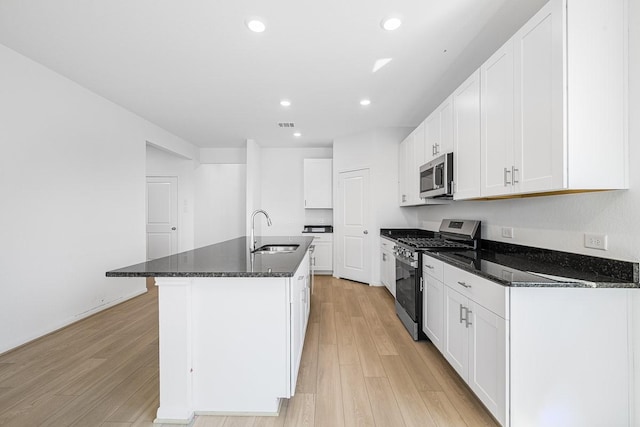 kitchen with an island with sink, light wood-style flooring, a sink, recessed lighting, and stainless steel appliances