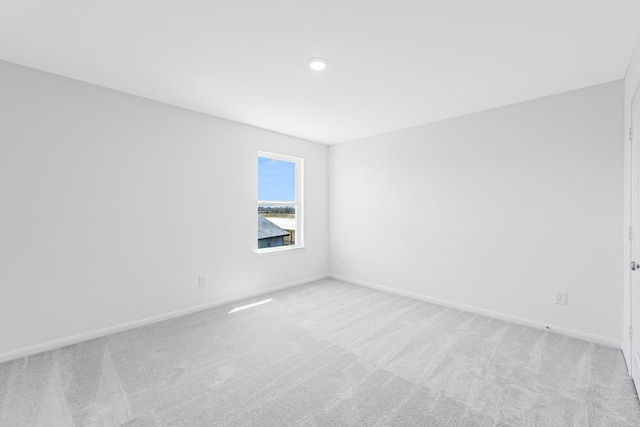 spare room featuring light carpet and baseboards