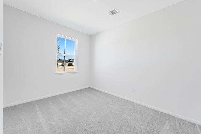 carpeted spare room with visible vents and baseboards