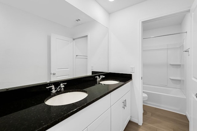 bathroom with a sink, toilet, wood finished floors, and double vanity