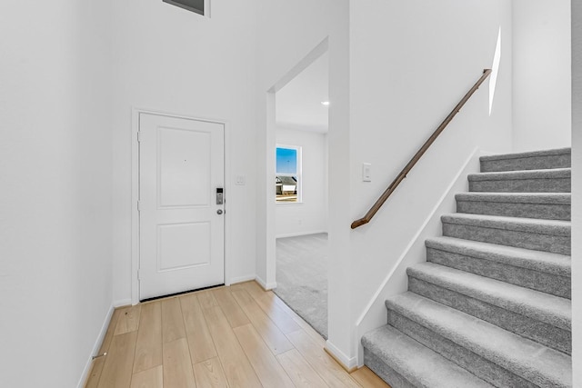 entrance foyer with stairway, baseboards, and light wood-style floors