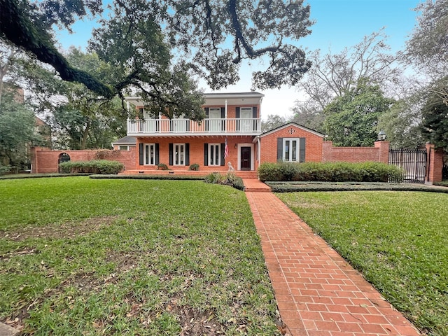 view of front of home featuring a balcony, fence, a front lawn, and brick siding