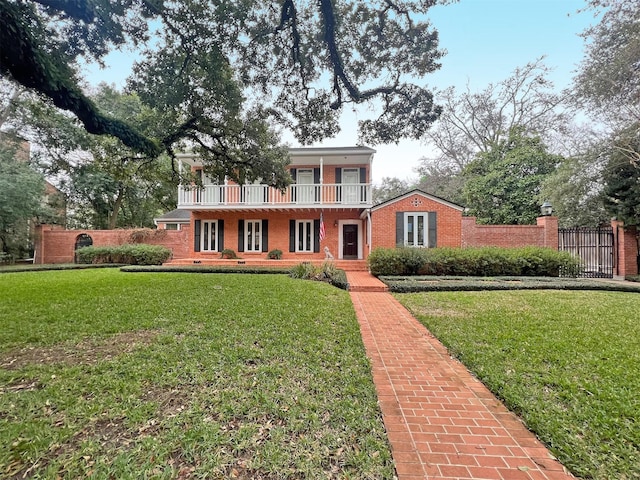 view of front of house featuring brick siding, a front yard, crawl space, fence, and a balcony