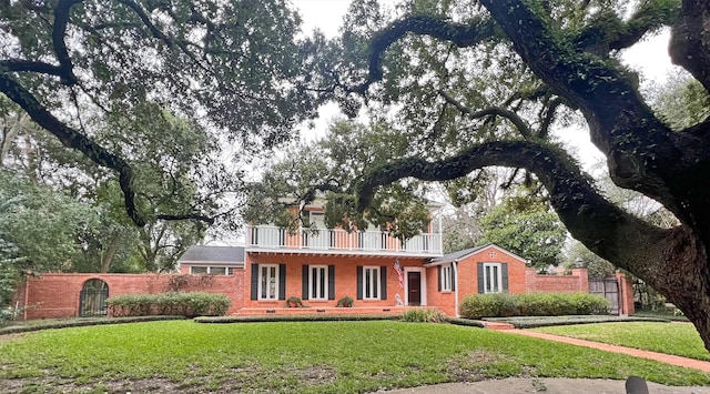 view of front of property featuring brick siding, a balcony, crawl space, fence, and a front yard