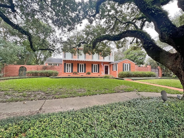 view of front of property with a front lawn, fence, and brick siding