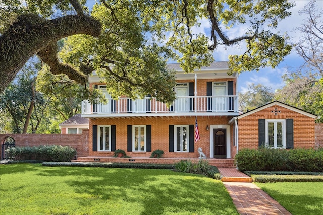 view of front facade with brick siding, a porch, a balcony, and a front yard