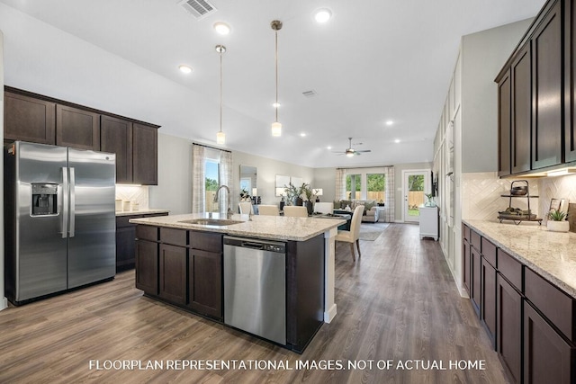 kitchen with dark brown cabinetry, dark wood-style floors, appliances with stainless steel finishes, open floor plan, and a sink