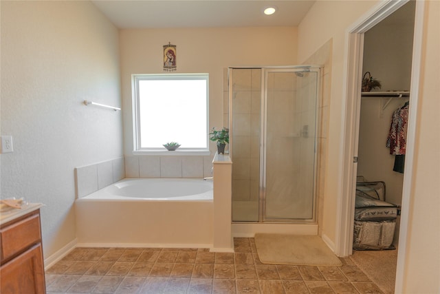 full bathroom with a garden tub, a shower stall, a walk in closet, and vanity