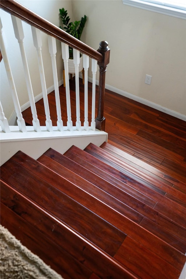 staircase with baseboards and wood finished floors