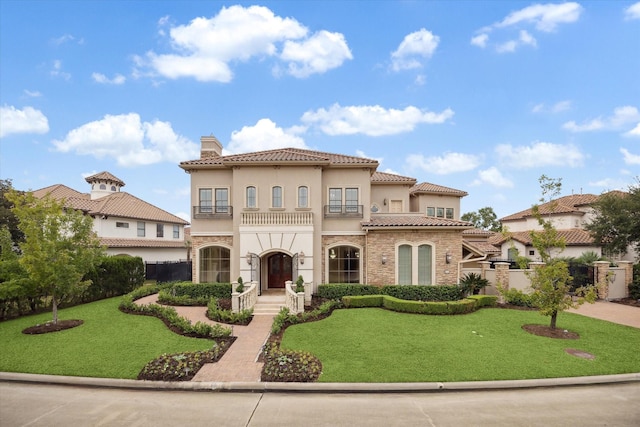 mediterranean / spanish-style home featuring fence, a chimney, a front lawn, and stucco siding