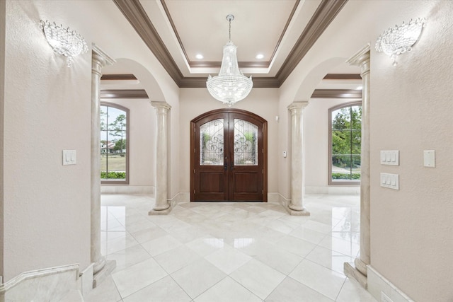 foyer entrance featuring ornate columns, crown molding, arched walkways, and a tray ceiling