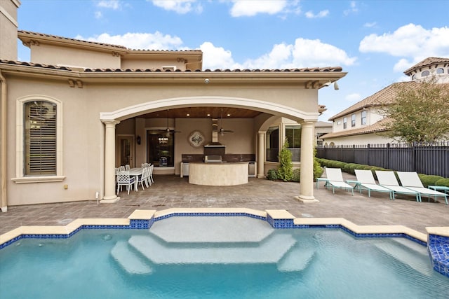 rear view of property featuring a fenced in pool, a patio, stucco siding, an outdoor kitchen, and fence