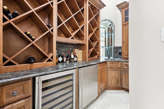 wine area featuring beverage cooler, a bar, light tile patterned flooring, and a sink